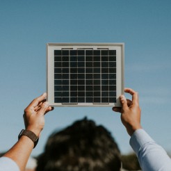 Eine Person hält ein Solarmodul in den Himmel